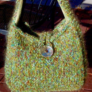 May include: A green, brown, and blue knitted handbag with a large, round, decorative button.