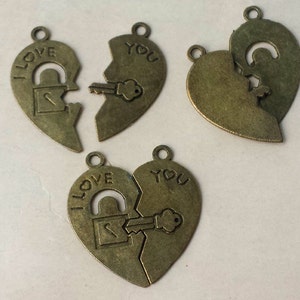 May include: Antique bronze-colored heart-shaped pendants. Each pendant is split in two, with one half reading "I LOVE" and the other half reading "YOU". One pendant features a key fitting into a lock.