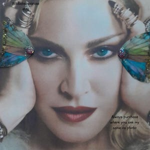 May include: A pair of decorative butterfly wing accessories featuring a gradient of blue, green, and purple hues with gold glitter accents and a central pink rhinestone. The image includes the text Wildbohemianrose etsy and Always purchase where you see my name on photo.