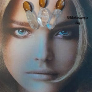 May include: Three hair pins featuring oval tiger's eye stones attached to clear, pointed quartz crystals. The image includes the text Wildbohemianrose etsy and Always purchase where you see my logo on photo. The pins are displayed over a face.
