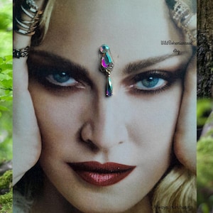 May include: A close-up of a woman's face with a jeweled forehead ornament. The ornament has a teardrop-shaped pendant with iridescent colours. The image includes the text "WildBohemianrose etsy" and "Always purchase where you see my name on photo."