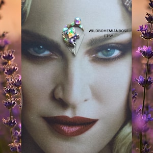 May include: A silver-toned fairy figurine with iridescent wings and a moon crescent, set against a lavender background. The fairy is holding a small, iridescent sphere. The text "WILDBOHEMIANROSE ETSY" is visible in the image.