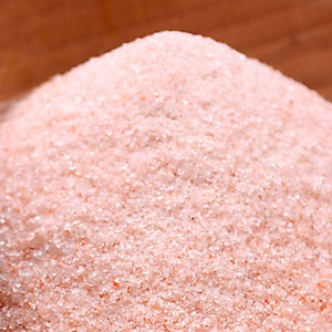 May include: Close-up of fine pink Himalayan salt crystals. The salt is a light pink color and has a grainy texture.