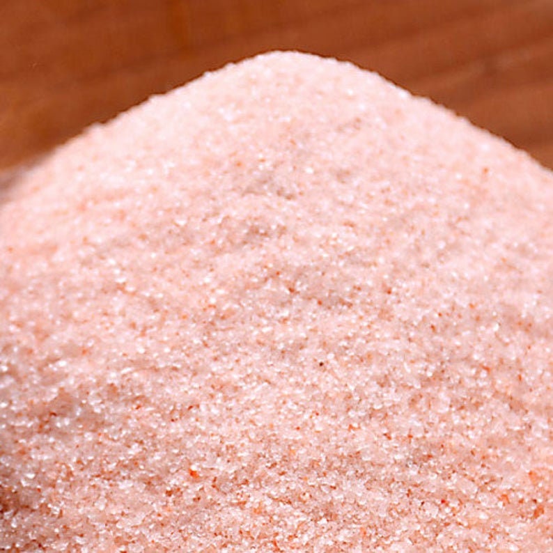 May include: Close-up of fine pink Himalayan salt crystals. The salt is a light pink color and has a grainy texture.