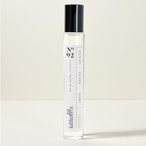 May include: A clear glass roll-on bottle with a black cap. The label reads "Posset Katiliz & Co.  Eau de Parfum No. 92 Lemon Matcha Oat Milk"