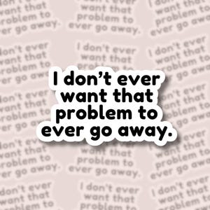 May include: A white sticker with the text "I don't ever want that problem to ever go away" in a bold, black font. The sticker has a white border and is set against a light pink background with the same text repeated.