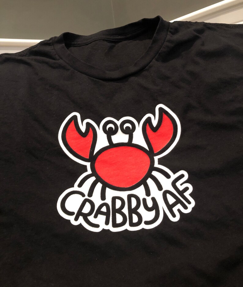 black t-shirt with a minimalist graphic crab illustration with hand lettering Crabby AF