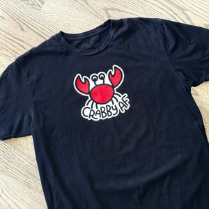 blackt-shirt with a minimalist graphic crab illustration with hand lettering Crabby AF