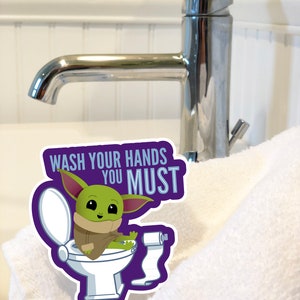 Vibrant Baby Yoda vinyl sticker. Baby Yoda is sitting on the toilet saying Wash Your Hands You Must