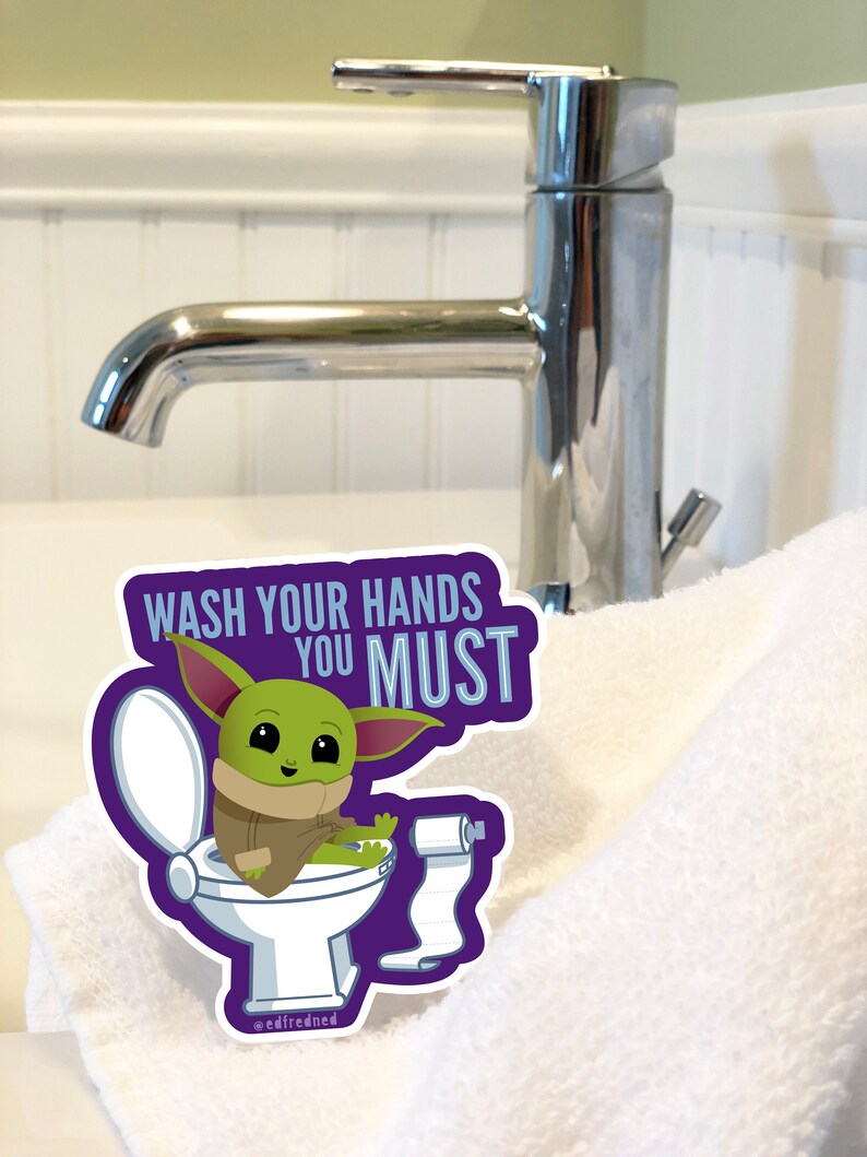 Vibrant Baby Yoda vinyl sticker. Baby Yoda is sitting on the toilet saying Wash Your Hands You Must