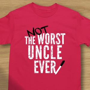 May include: Pink t-shirt with a white graphic that says "Not the worst uncle ever" with a check mark next to the word "ever".