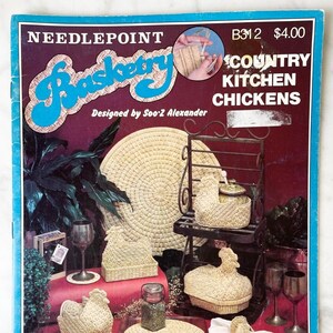 May include: A needlepoint craft book with a blue cover featuring the title "Basketry: Country Kitchen Chickens" and a close-up image of a woven chicken. The book includes 8 projects combining plastic canvas and natural raffia.