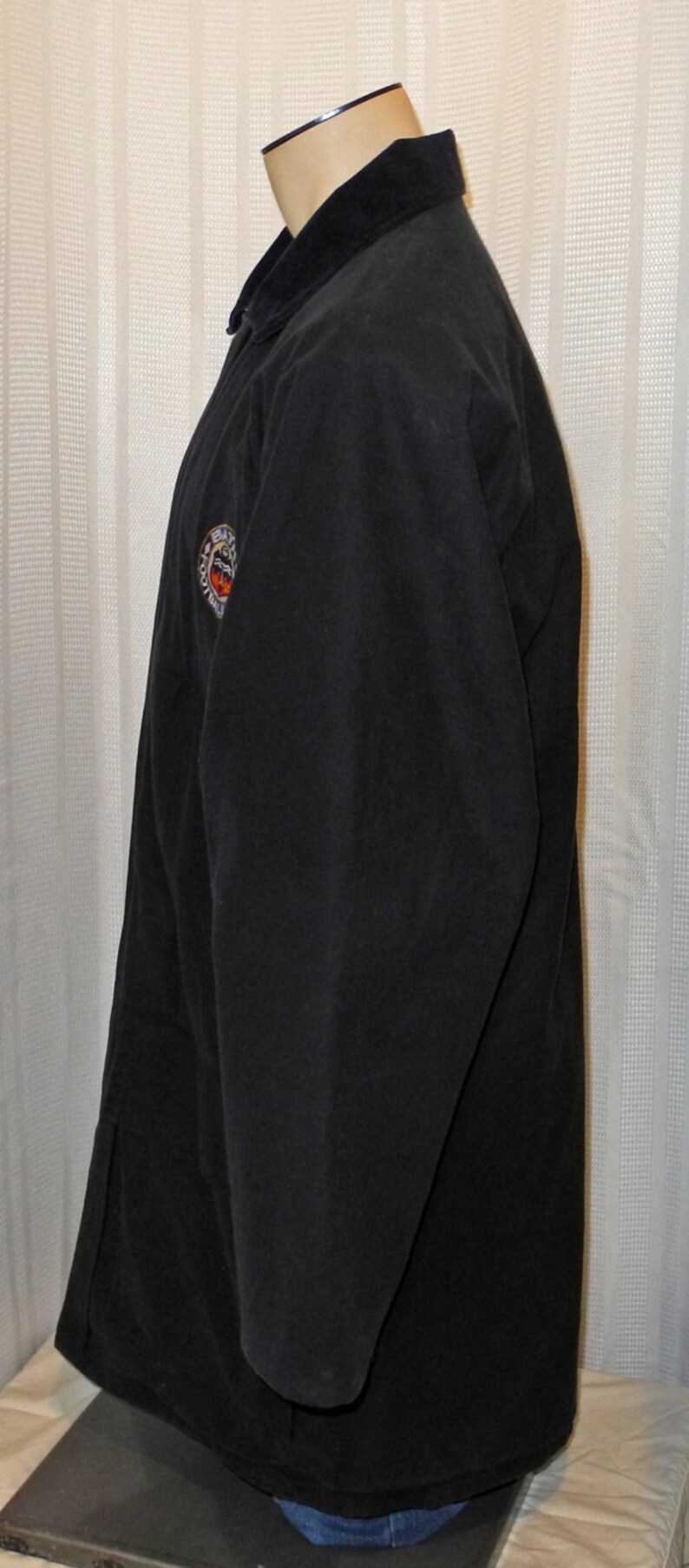 May include: A black long-sleeved jacket with a zipper closure and a circular patch on the left sleeve that says "Batman" with a bat logo.