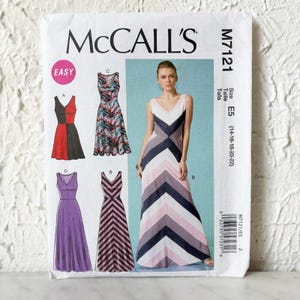 May include: McCall's M7121 sewing pattern envelope featuring illustrations of four sleeveless dress variations. The designs include a color-blocked dress, a patterned dress, a solid purple dress, and a chevron-striped dress in pink, white, and navy.