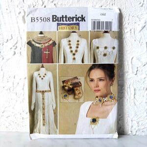 May include: A Butterick B5508 sewing pattern envelope for historical jewelry, featuring illustrations of various necklaces, a belt, and a brooch with gold-tone metal, pearls, and blue or red stones displayed on garments and as individual items.