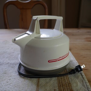 May include: White electric kettle with a black cord and plug. The kettle has a red stripe with the word "Presto" on it.