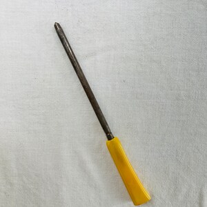May include: A long, thin, metal knife sharpener with a yellow plastic handle.