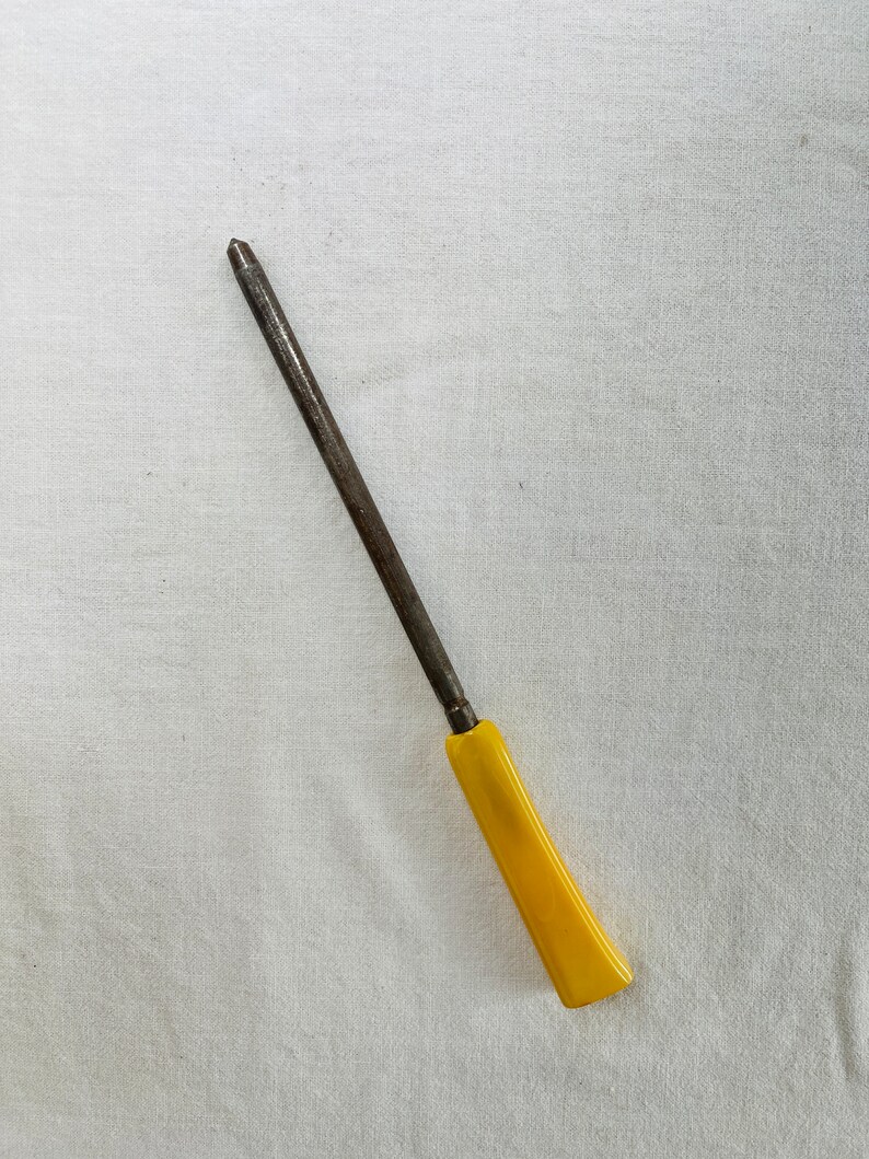 May include: A long, thin, metal knife sharpener with a yellow plastic handle.
