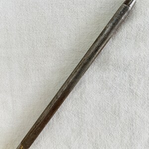 May include: A close-up of a metal sharpening steel with a yellow plastic handle. The steel is used to sharpen knives.