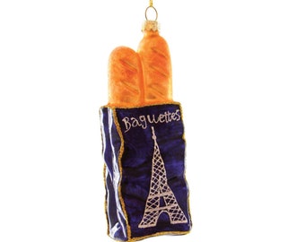 May include: A blue glass Christmas ornament shaped like a bag of baguettes with the Eiffel Tower on the front. The bag has gold glitter trim and the text "Baguettes" is printed on the front.