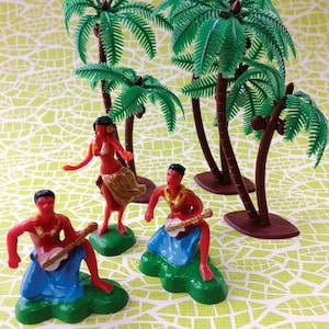 May include: A set of four plastic figurines depicting Hawaiian dancers and palm trees. The figurines are red, blue, green, and brown. The palm trees are green and brown.