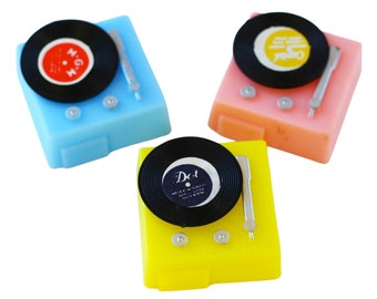 May include: Three miniature toy record players, one blue, one pink, and one yellow, each with a black vinyl record and a silver tone arm.