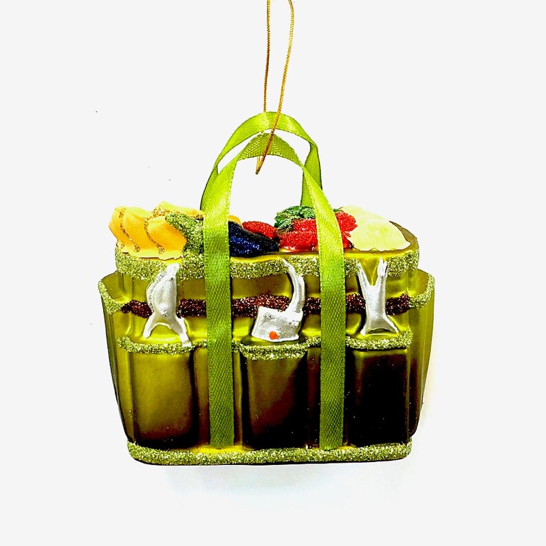 Pode incluir: Enfeite de Natal decorativo em forma de cesta de piquenique verde. A cesta tem uma al&ccedil;a verde e &eacute; preenchida com alimentos coloridos em miniatura. O enfeite tem tr&ecirc;s bolsos na frente e &eacute; adornado com glitter.