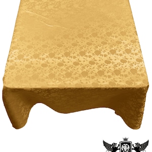 May include: A gold tablecloth with a floral pattern. The tablecloth is made of a satin-like material and has a subtle sheen.