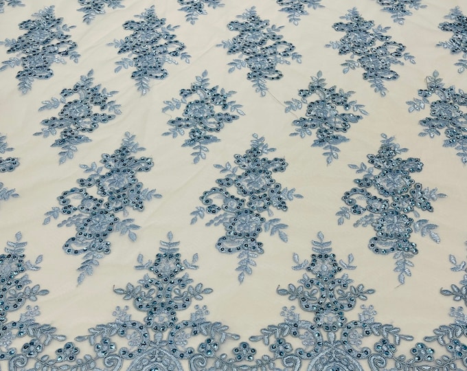 Light blue corded flowers embroider with sequins on a mesh lace fabric-sold by the yard.
