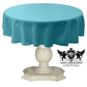 May include: A teal round tablecloth draped over a white pedestal table. The tablecloth is smooth and has a slight sheen. The table has a round top and a pedestal base with a decorative design. The text "NEW CREATIONS FABRIC & FOAM" is visible in the lower right corner of the image.