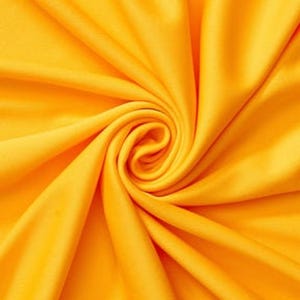 Könnte beinhalten: Ein einfarbiger, leuchtend gelber Stoff mit einer glatten, matten Textur. Das Material ist in einem zentralen Spiralwirbelmuster angeordnet, wodurch tiefe, fließende Falten und Schatten entstehen, die vom Mittelpunkt des Textils ausgehen.