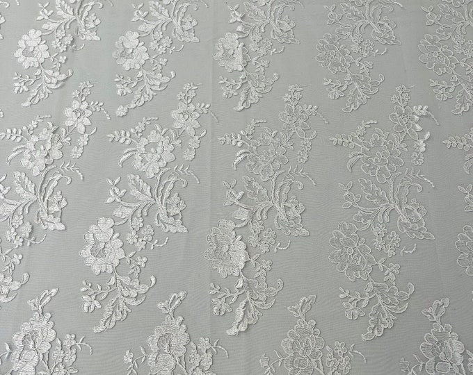 White floral design embroider and corded on a mesh lace fabric-sold by the yard.