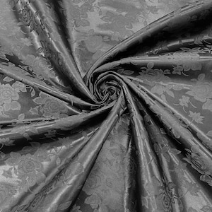 以下が含まれることがあります： 花柄の黒い布。布がドレープされ、折り畳まれ、中央に渦巻きが生まれています。