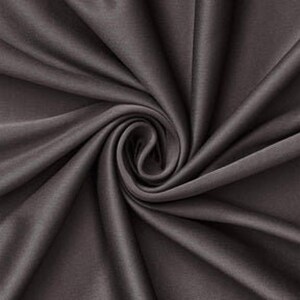 Könnte beinhalten: Ein einfarbiger, dunkel anthrazitfarbener Stoff mit einer glatten, matten Textur. Das Material ist in einem zentralen Spiralmuster angeordnet, wodurch tiefe, fließende Falten und Schatten entstehen, die vom Mittelpunkt des Textils ausgehen.