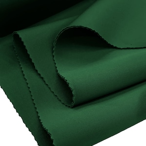 May include: A close-up of a deep green fabric with a smooth texture. The fabric is folded in half and the edges are slightly frayed.