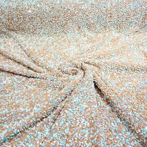 Puede incluir: Primer plano de una tela beige con lentejuelas iridiscentes. Las lentejuelas están dispersas aleatoriamente por la tela, creando un efecto brillante.