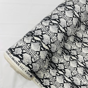 May include: A roll of white fabric with a black snake skin pattern. The fabric is labelled "Patti # 7577 "PYTHON" ".