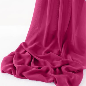 May include: A vibrant pink sheer fabric draped over a white surface. The fabric is soft and flowing, with a delicate texture.