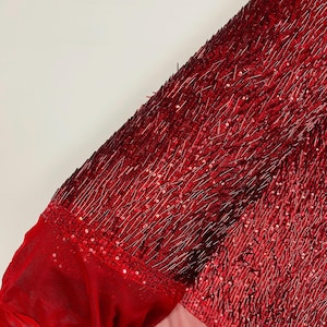 May include: Red beaded fabric with a sheer mesh backing. The beads are arranged in a vertical pattern, creating a textured look.
