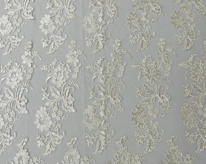 Ivory floral design embroider and corded on a mesh lace fabric-sold by the yard.