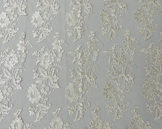 Ivory floral design embroider and corded on a mesh lace fabric-sold by the yard.