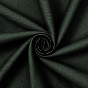 Pode incluir: Um tecido verde-floresta escuro com um padrão distinto de sarja diagonal. O material está disposto numa espiral central, criando sombras e luzes profundas que enfatizam a textura e a trama densa e uniforme do material têxtil em questão.