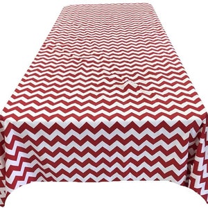 May include: Red and white chevron patterned tablecloth. The tablecloth is made of a smooth, wrinkle-resistant fabric.
