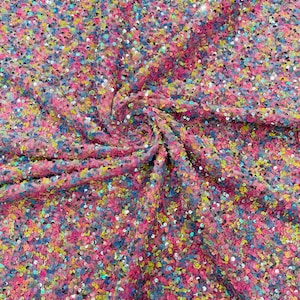 May include: A close-up of a pink fabric with iridescent sequins in various colors, including blue, green, yellow, and pink.