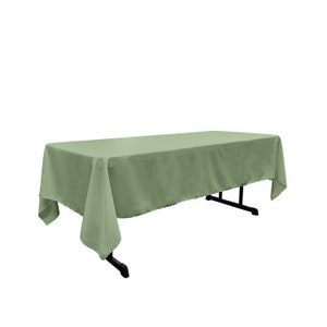 Puede incluir: Un mantel rectangular de color verde salvia drapeado sobre una mesa. El mantel tiene un acabado liso y sin arrugas.