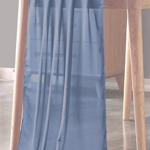 May include: A light blue table runner draped over a wooden table. The runner is made of a sheer fabric and hangs down, creating soft folds. The table has light-colored wooden legs and a matching wooden top.