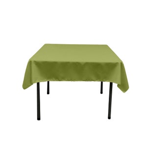 May include: A square green tablecloth draped over a black table with four legs.