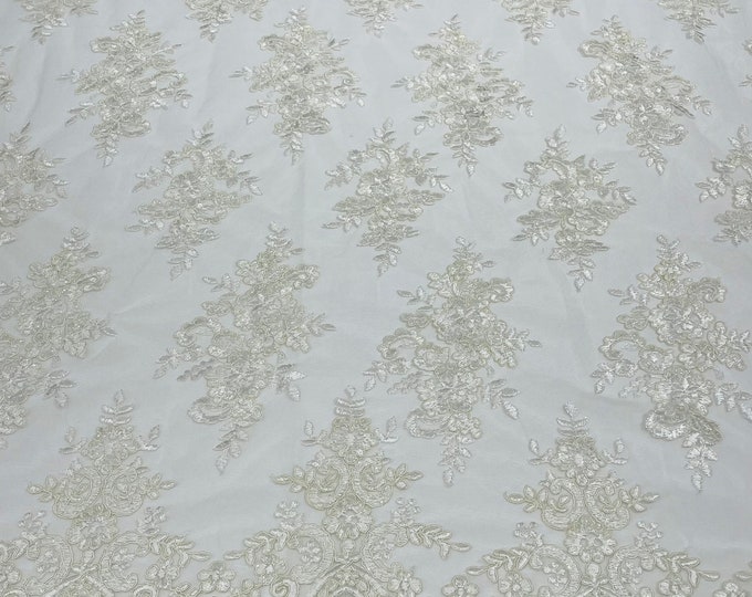 Off White corded flowers embroider with sequins on a mesh lace fabric-sold by the yard.