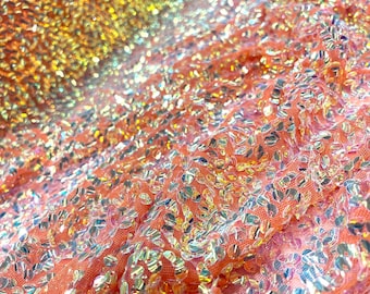 Aqua Clear iridescent mini round paillette sequins embroidered on a orange stretch mesh, sold by the yard.