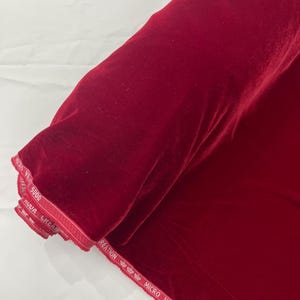 May include: A roll of deep red micro velvet fabric with white text on the edge that reads "Creation Micro Velvet 5000".